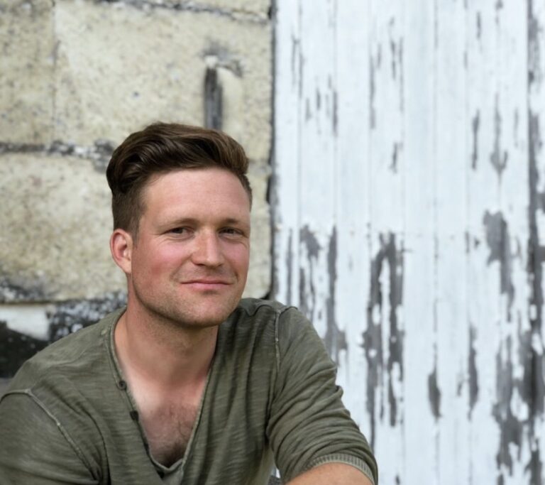 Man in green shirt sitting in front of white fence