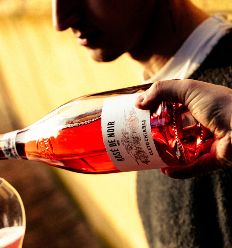 person pouring rose wine out of a bottle into a glass