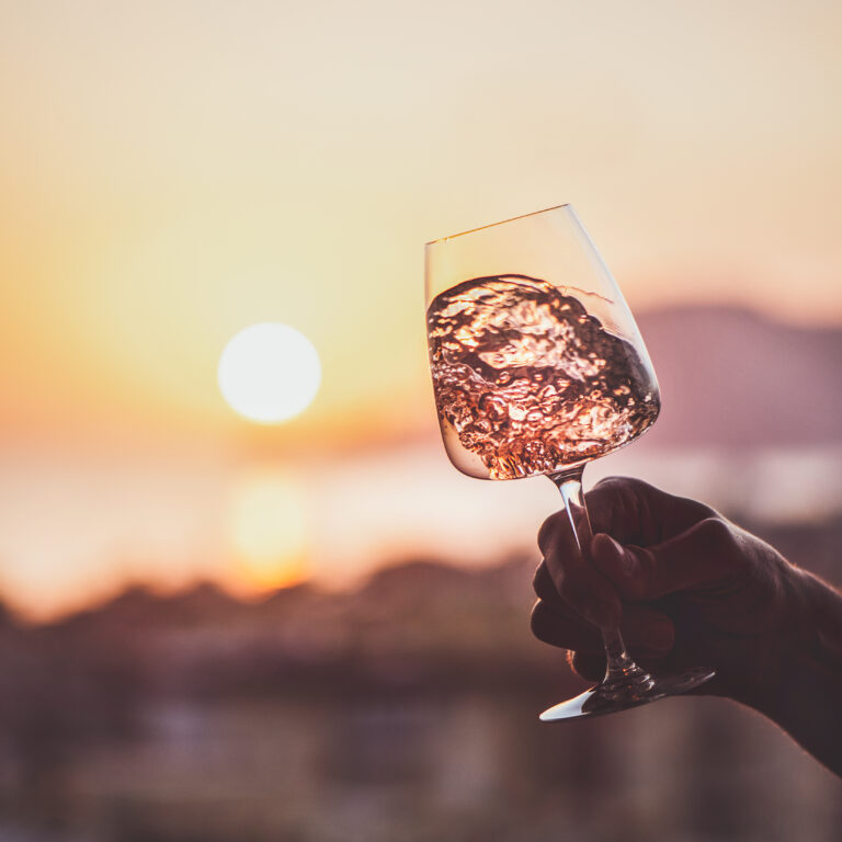 wine swirled in a glass in front of a sunset